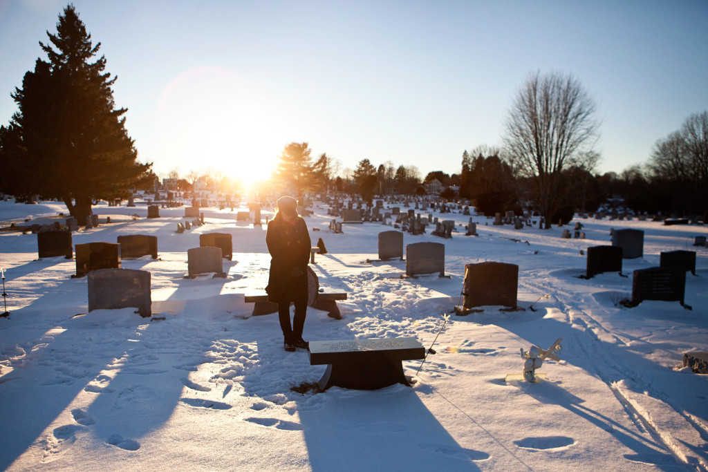Portsmouth, NH -- 01/21/16 -- Paula Skelley stands at her daughter Lydia's gravesite bench in the South Cemetery on January 21, 2016, in Portsmouth, New Hampshire. Lydia's gravesite is directly across a small pond from "Lydia's Garden", a memorial space dedicated to her which is located on a section of the playground of her former school, the Little Harbour School. Lydia specifically requested to be buried in this cemetery to be close to her school. She was buried right in front of the grave of a young girl, Hannah, who's gravesite inspired the initial end of life conversations that Lydia and her mother eventually had during Lydia's struggle with cancer. (Kayana Szymczak for STAT)