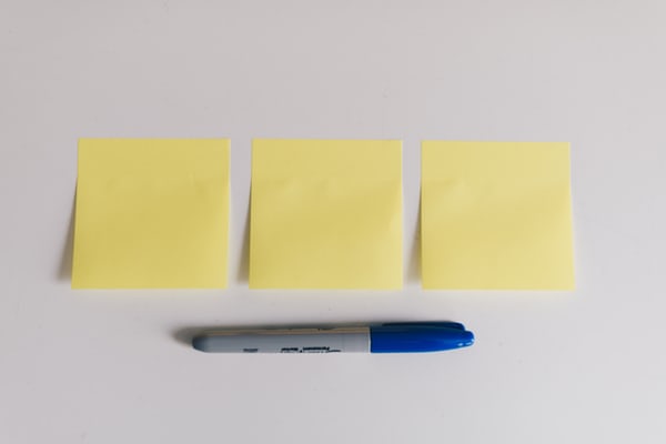 3 yellow sticky notes in a horizontal row with a blue marker placed underneath.