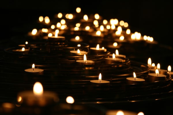 Several lit tea light candles against a black background
